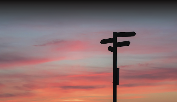 directional sign in front of sunset